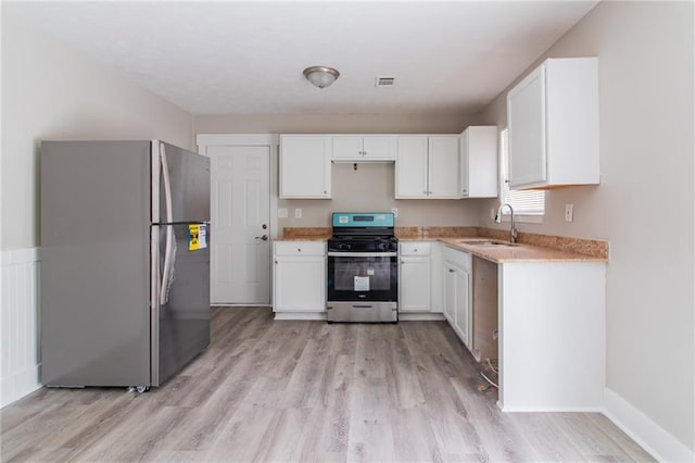 kitchen featuring visible vents, white cabinets, light wood-style flooring, appliances with stainless steel finishes, and a sink