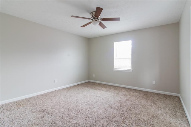 carpeted empty room featuring baseboards and a ceiling fan