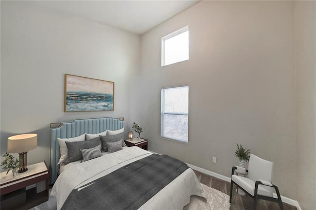 bedroom with a towering ceiling, baseboards, and wood finished floors