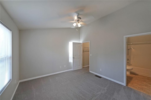 unfurnished bedroom with lofted ceiling, carpet, baseboards, and a walk in closet