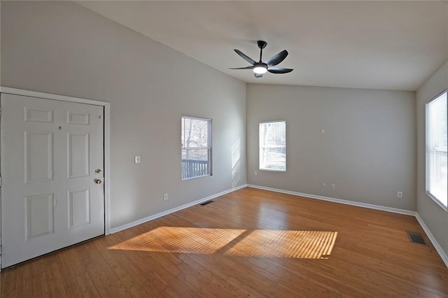 spare room featuring vaulted ceiling, light wood finished floors, visible vents, and baseboards