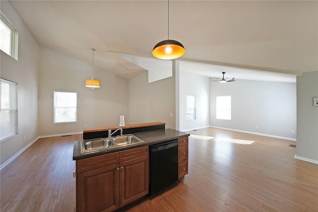 kitchen featuring dark countertops, a sink, open floor plan, and dishwasher