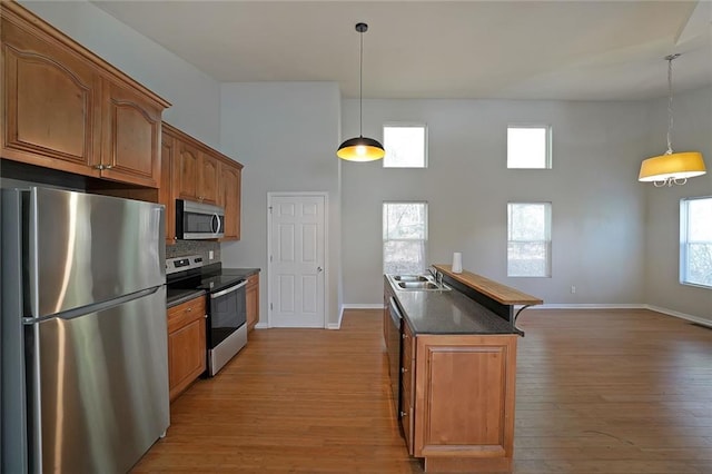 kitchen featuring appliances with stainless steel finishes, dark countertops, brown cabinets, and a sink