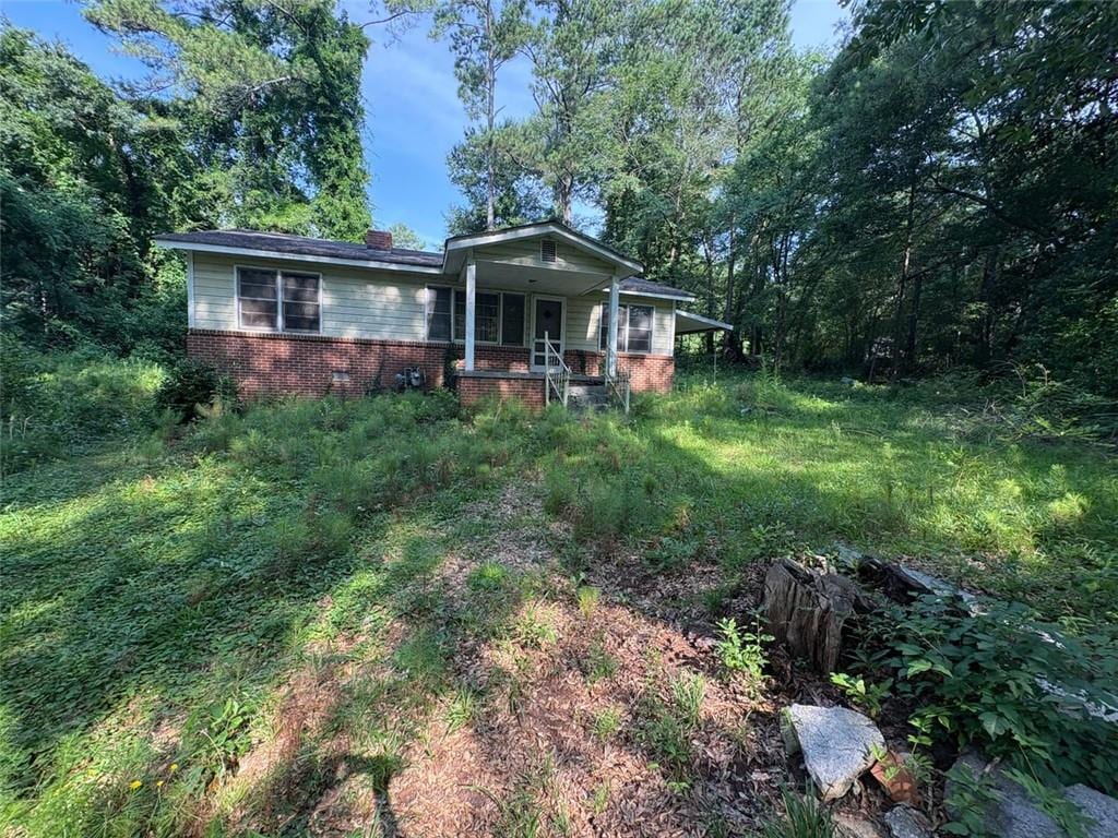 5103 NW Berry St NW, Covington, GA 30014 - view of front of house with brick siding, a porch, and a chimney