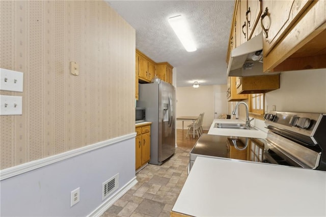 136 Pine St, Covington, GA 30014 - kitchen featuring appliances with stainless steel finishes, under cabinet range hood, stone finish floors, light countertops, and a textured ceiling