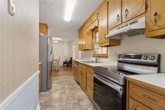 136 Pine St, Covington, GA 30014 - kitchen featuring appliances with stainless steel finishes, under cabinet range hood, light countertops, brown cabinets, and a textured ceiling