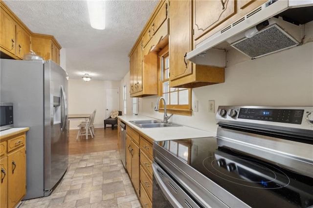 136 Pine St, Covington, GA 30014 - kitchen featuring stainless steel appliances, under cabinet range hood, light countertops, stone finish floors, and a textured ceiling