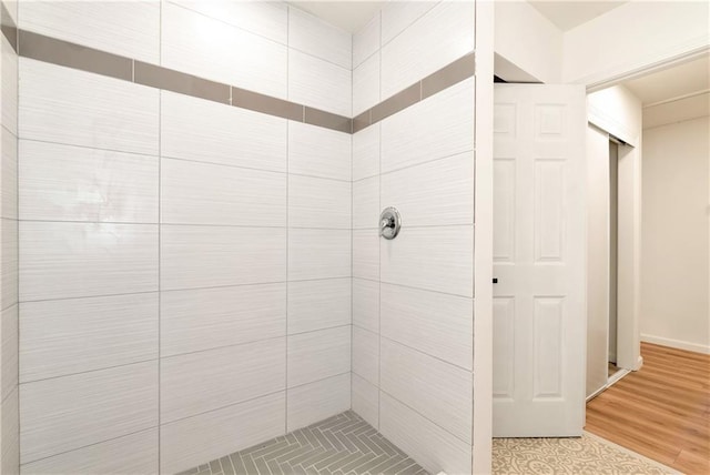 bathroom with a tile shower and hardwood / wood-style flooring