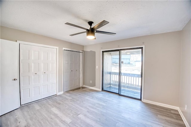 unfurnished bedroom featuring access to exterior, ceiling fan, multiple closets, a textured ceiling, and light hardwood / wood-style flooring