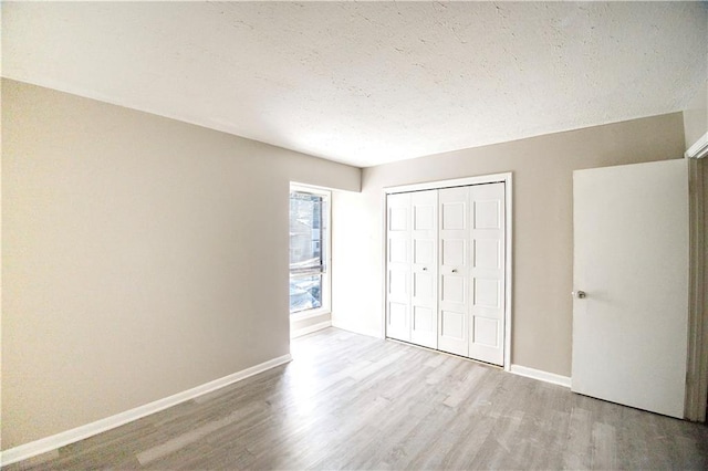 unfurnished bedroom featuring a textured ceiling, light wood-type flooring, and a closet