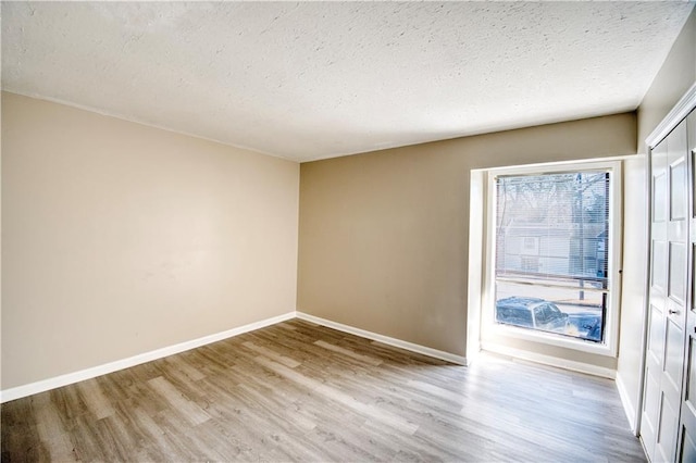 unfurnished room with light hardwood / wood-style flooring and a textured ceiling