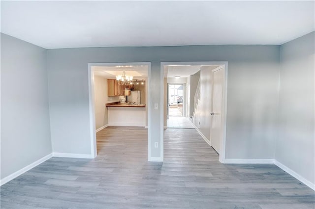 empty room featuring an inviting chandelier and light hardwood / wood-style flooring