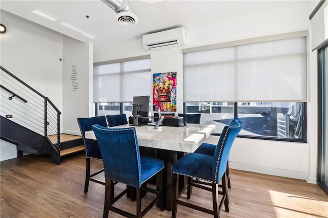 dining space featuring an AC wall unit, light hardwood / wood-style flooring, and a healthy amount of sunlight