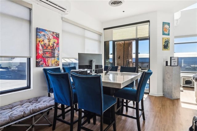 dining area featuring hardwood / wood-style floors and an AC wall unit