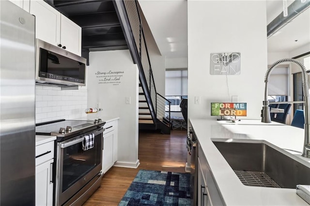 kitchen featuring appliances with stainless steel finishes, decorative backsplash, white cabinets, sink, and dark wood-type flooring
