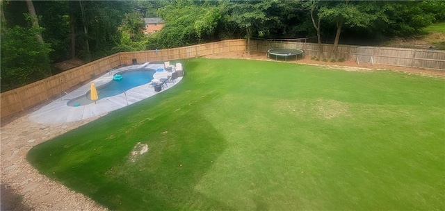 view of pool featuring a fenced backyard, a fenced in pool, a yard, and a trampoline