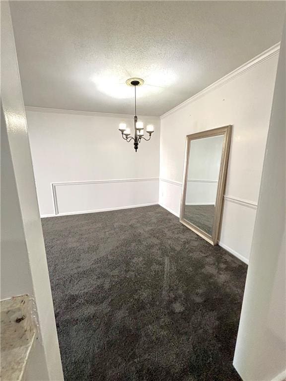 unfurnished dining area with ornamental molding, dark colored carpet, an inviting chandelier, and a textured ceiling
