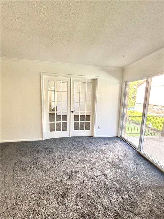 spare room featuring carpet, french doors, a textured ceiling, and baseboards