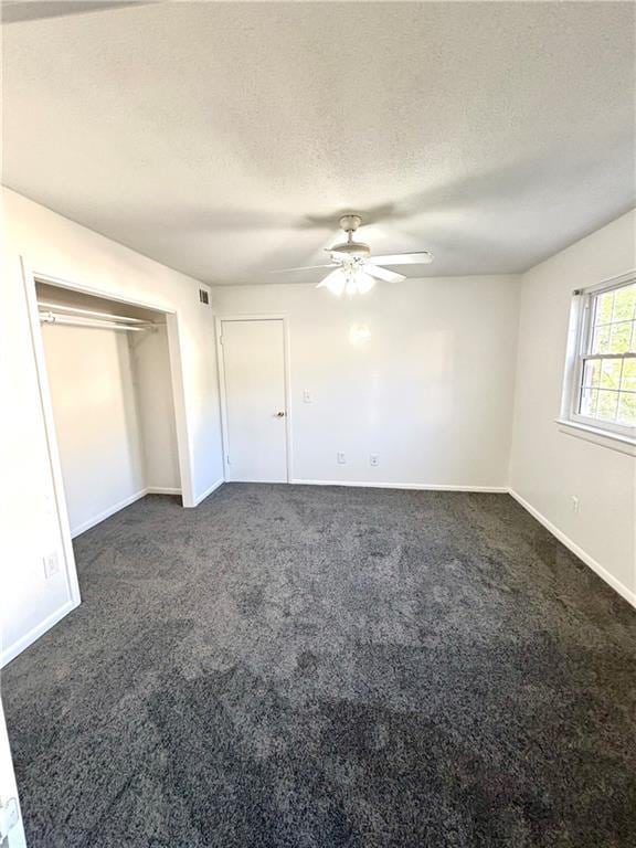unfurnished bedroom with dark carpet, baseboards, a ceiling fan, and a textured ceiling