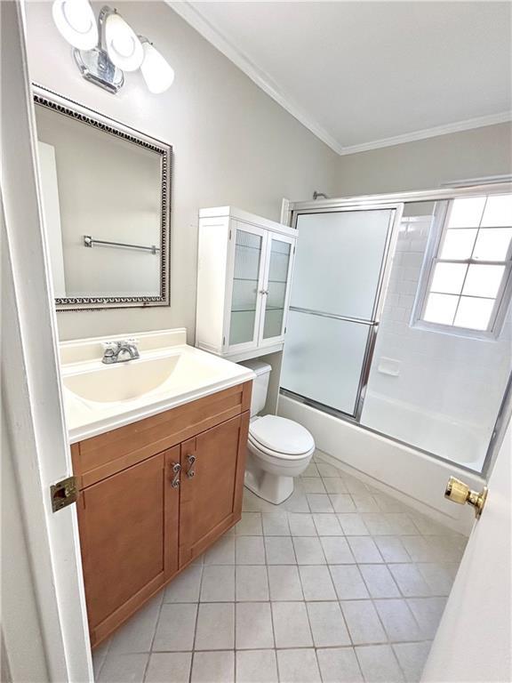 full bath featuring crown molding, vanity, tile patterned flooring, toilet, and bath / shower combo with glass door