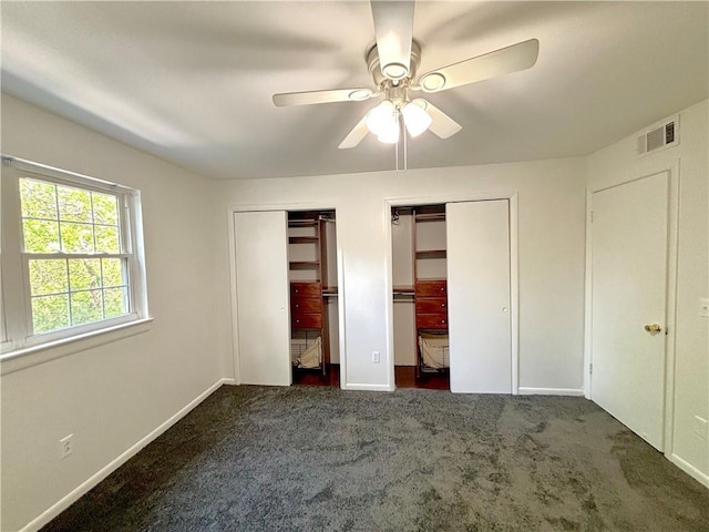 unfurnished bedroom with ceiling fan, carpet, visible vents, multiple closets, and baseboards