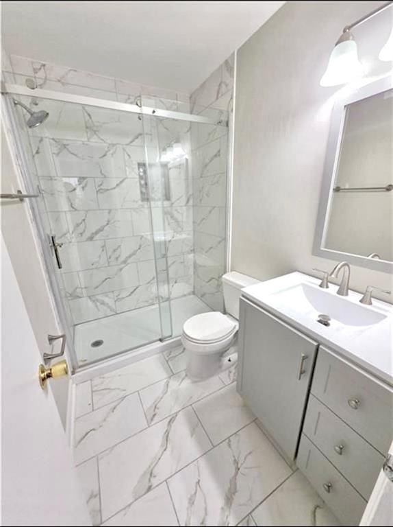 bathroom featuring vanity, marble finish floor, toilet, and a marble finish shower
