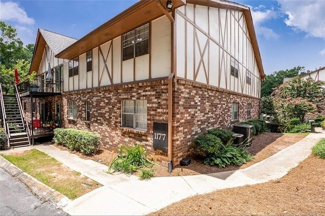 view of side of property featuring stairway, brick siding, board and batten siding, and central AC unit