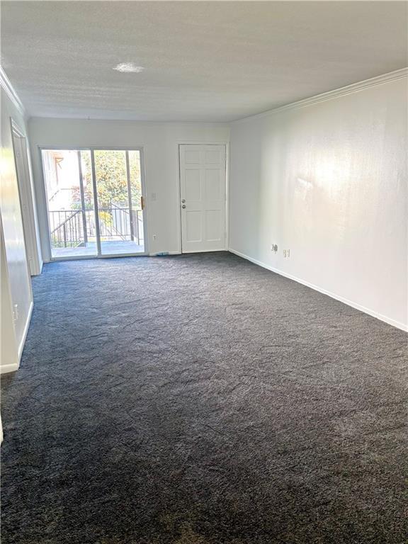empty room with crown molding, baseboards, and carpet floors