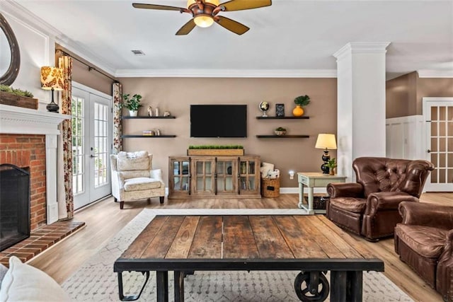 living room featuring light wood-type flooring, french doors, ornamental molding, and a fireplace