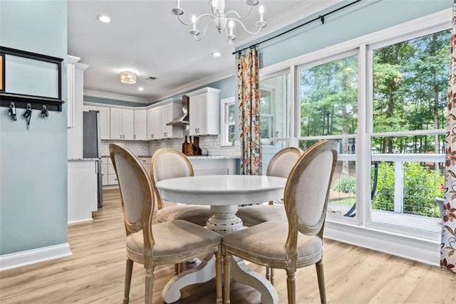 dining area with crown molding, light hardwood / wood-style floors, and a chandelier