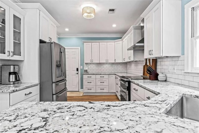 kitchen with white cabinets, stainless steel appliances, light stone countertops, and tasteful backsplash