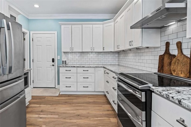 kitchen featuring white cabinets, wall chimney range hood, stainless steel appliances, tasteful backsplash, and light hardwood / wood-style floors