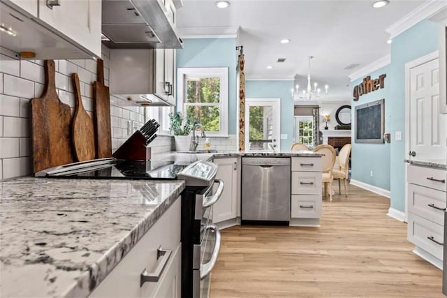 kitchen featuring crown molding, white cabinetry, exhaust hood, decorative backsplash, and stainless steel appliances