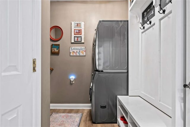 laundry area featuring stacked washer and clothes dryer and light hardwood / wood-style flooring