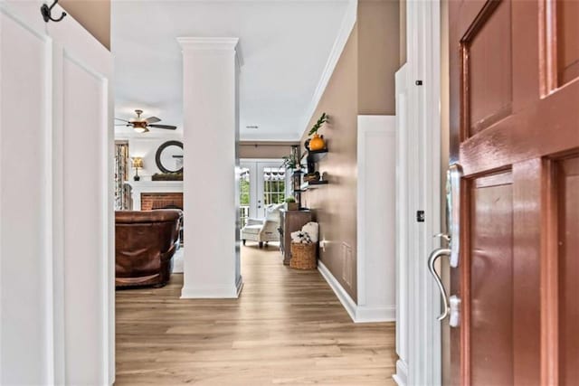 entryway with a fireplace, decorative columns, light wood-type flooring, french doors, and ornamental molding