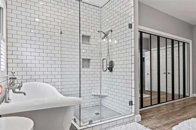 bathroom with wood-type flooring and shower with separate bathtub