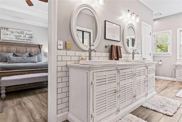 bathroom with crown molding, wood-type flooring, tile walls, vanity, and ceiling fan