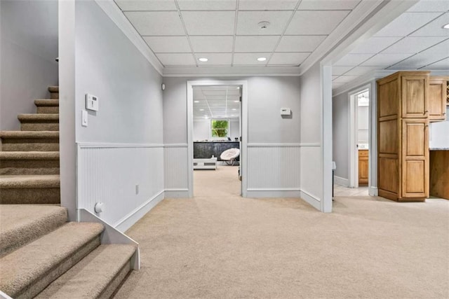 hall featuring light colored carpet, a drop ceiling, and crown molding