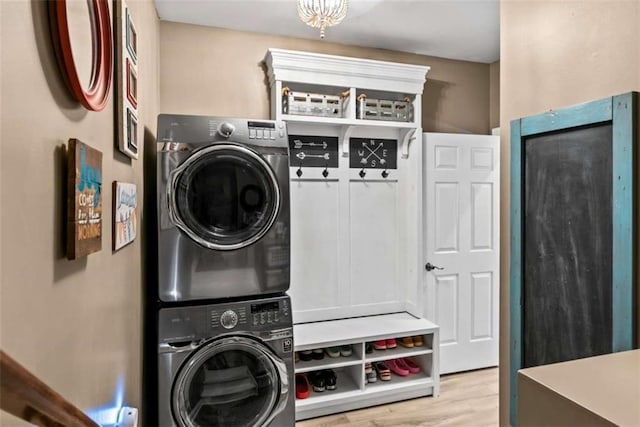 laundry room featuring stacked washing maching and dryer and light hardwood / wood-style flooring