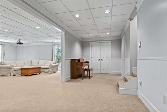 living room with light colored carpet, a paneled ceiling, and ornamental molding