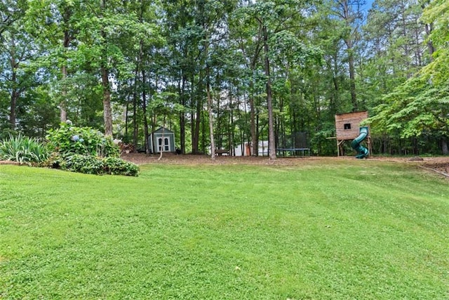 view of yard featuring a shed, a playground, and a trampoline