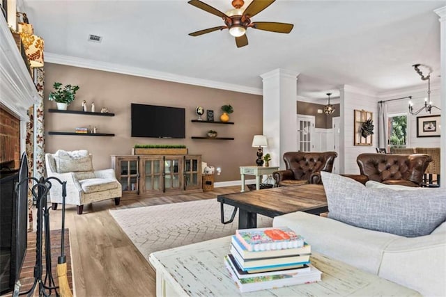 living room featuring hardwood / wood-style flooring, crown molding, ornate columns, and ceiling fan with notable chandelier