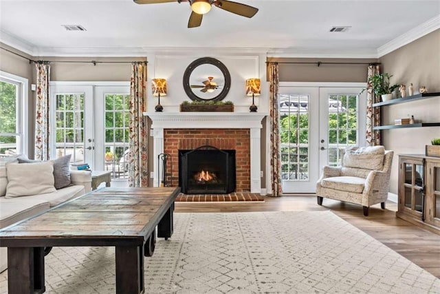 living room with ornamental molding, hardwood / wood-style floors, a brick fireplace, and french doors