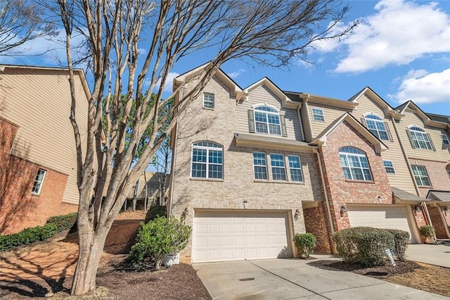 townhome / multi-family property with a garage, concrete driveway, and brick siding