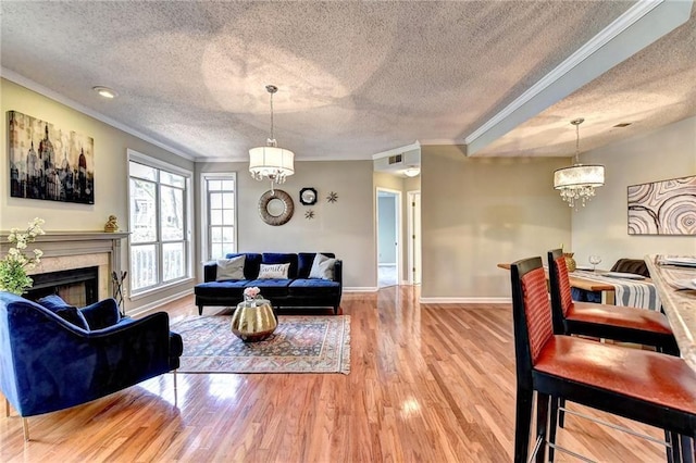 living room featuring ornamental molding, wood-type flooring, a notable chandelier, and a textured ceiling