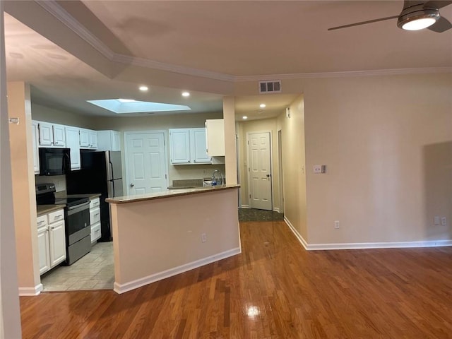 kitchen with white cabinetry, a skylight, ornamental molding, light hardwood / wood-style floors, and stainless steel electric stove