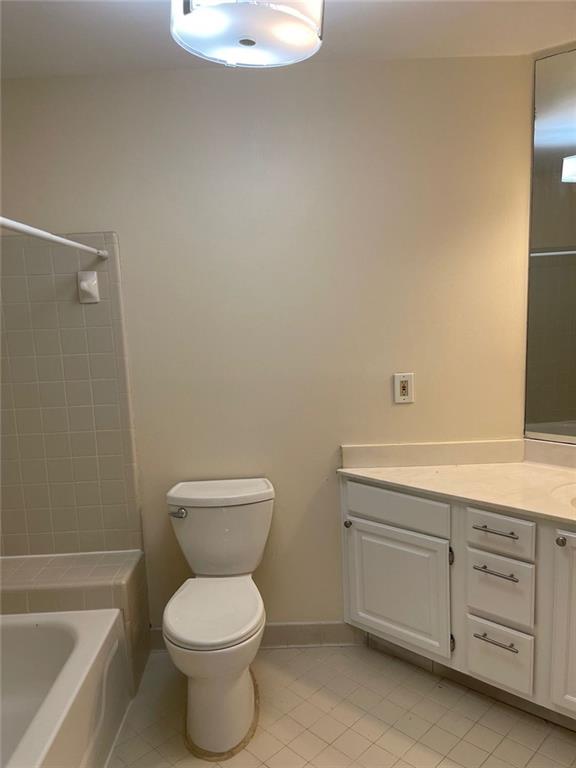 full bathroom with vanity, tile patterned flooring, tiled shower / bath combo, and toilet