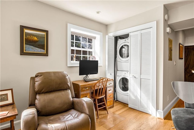 interior space with baseboards, stacked washer and dryer, and light wood finished floors