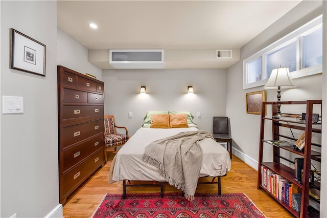 bedroom with light wood finished floors, visible vents, and baseboards