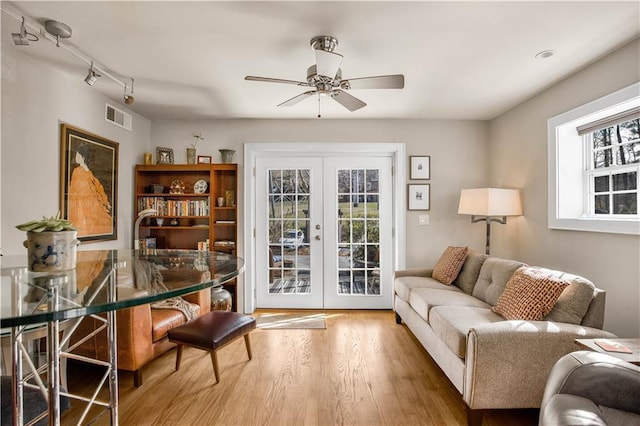 interior space with french doors, visible vents, wood finished floors, and a ceiling fan